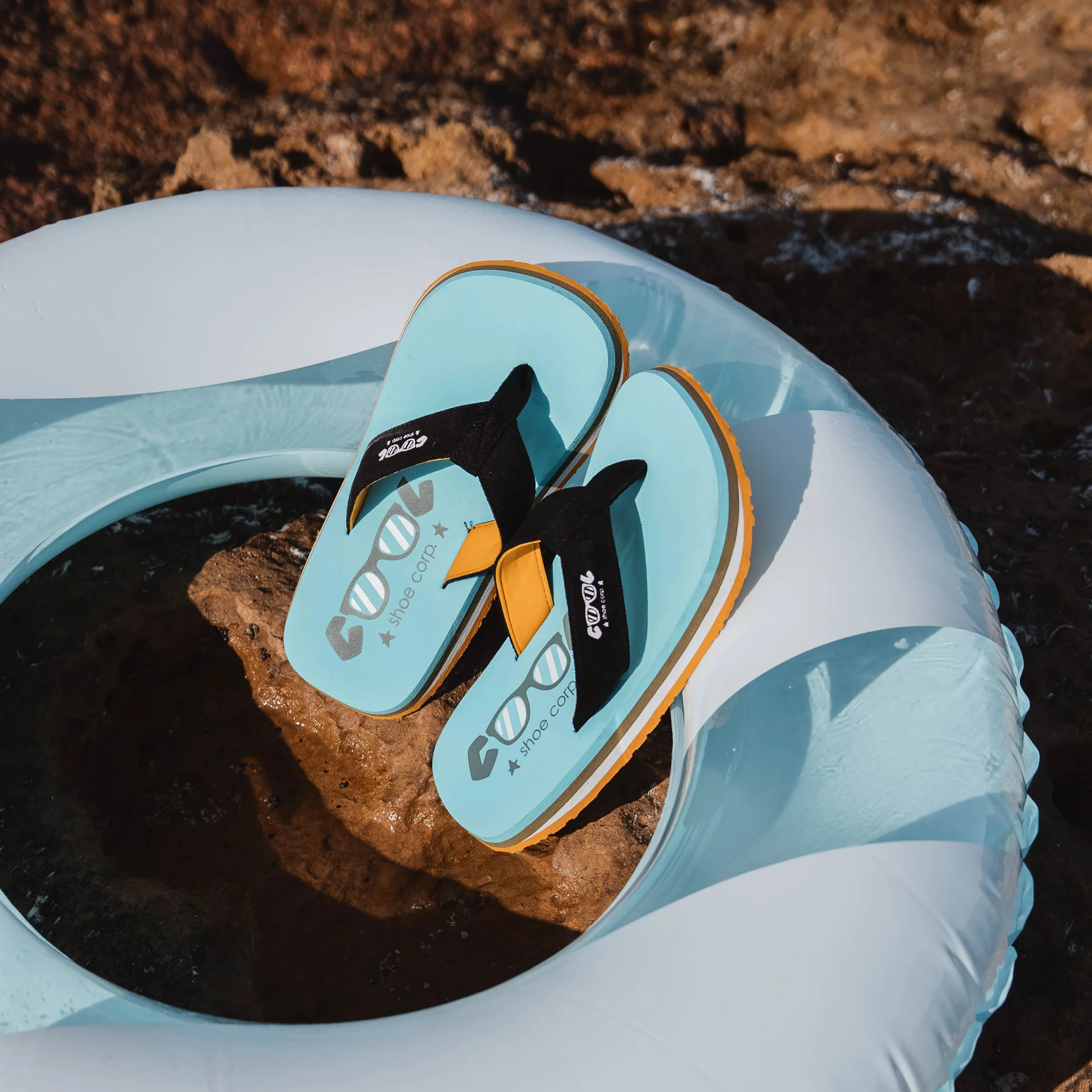Tongs Cool Shoe Corp posées sur une bouée, en bord de mer